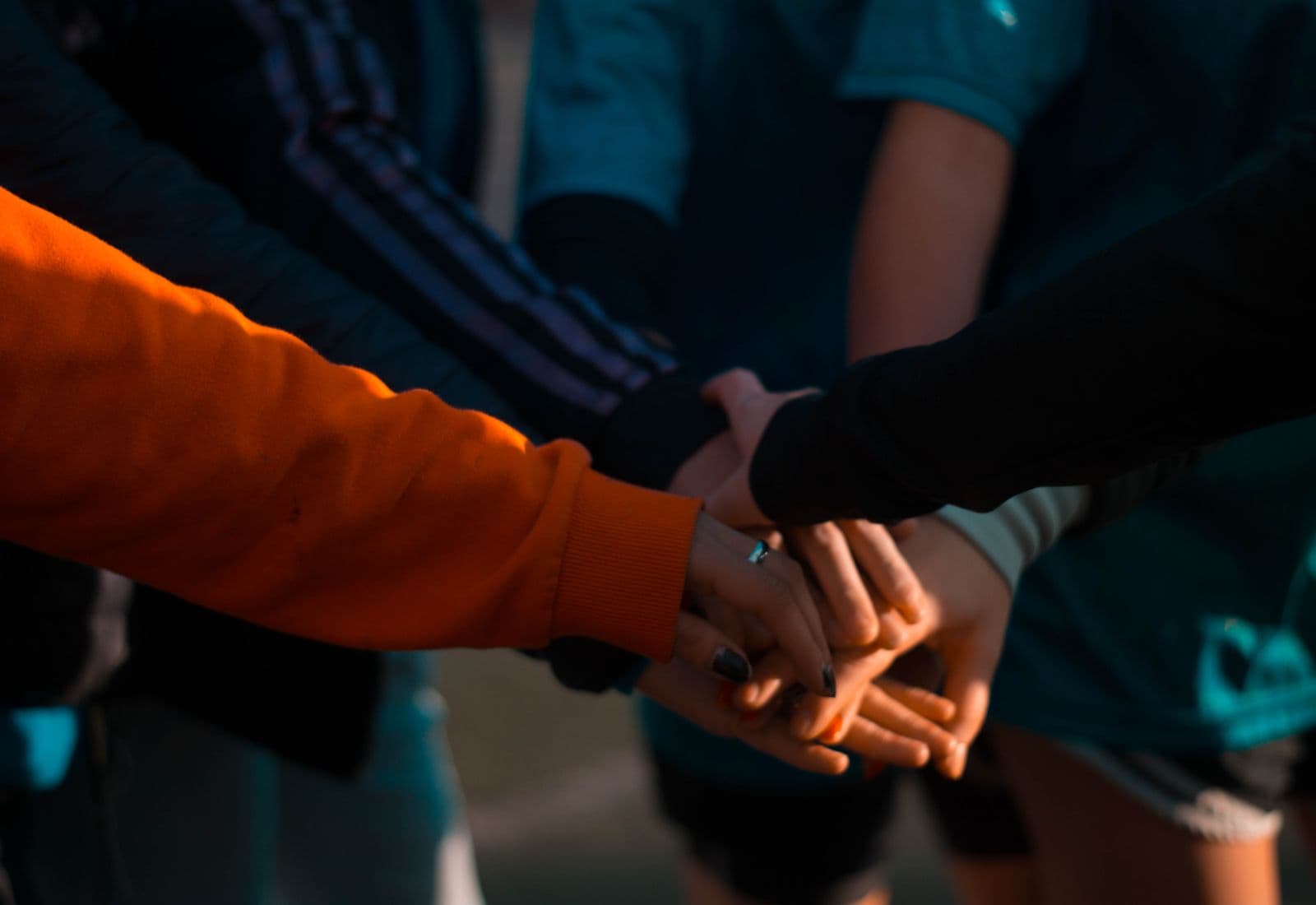 Several people stacking their hands together in a gesture of mutual support