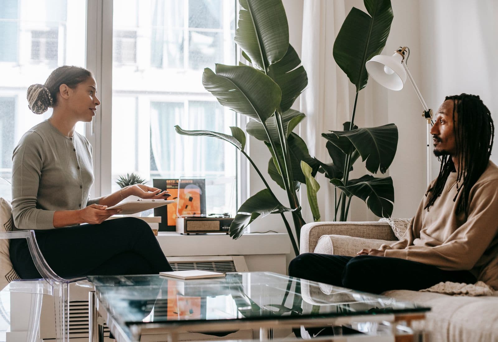 Two people in a bright, plant-filled room during a counselling session