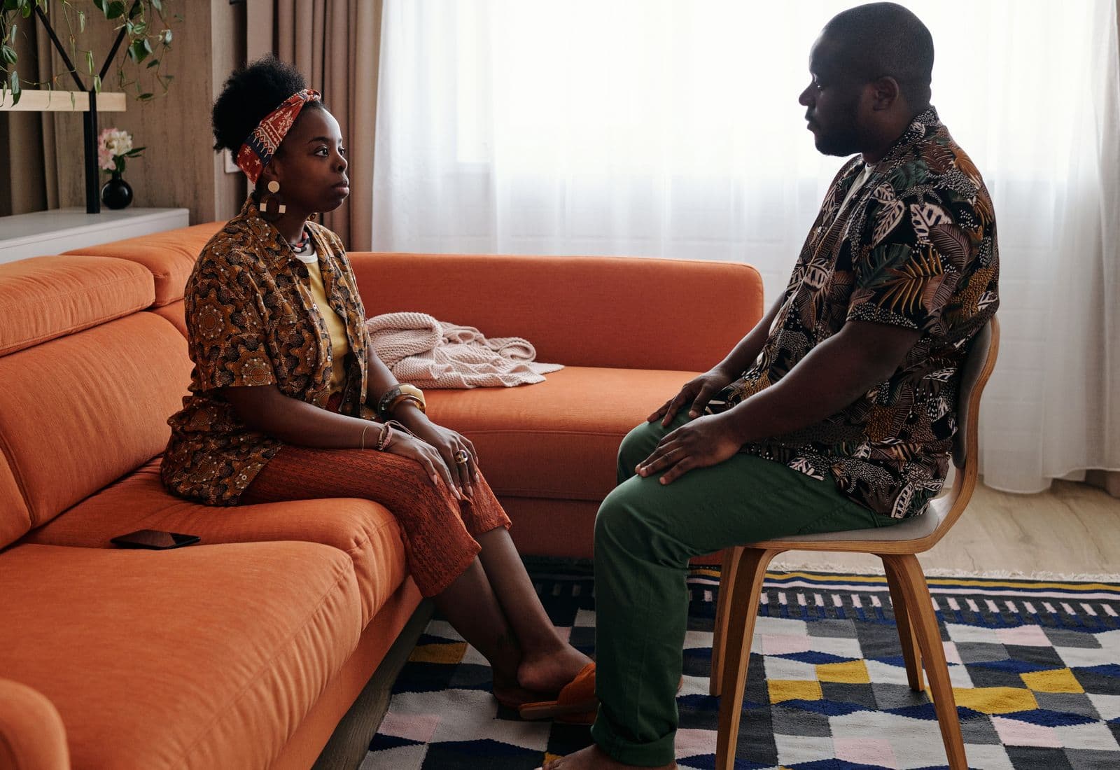 A couple sitting together on a sofa, turned towards each other in conversation